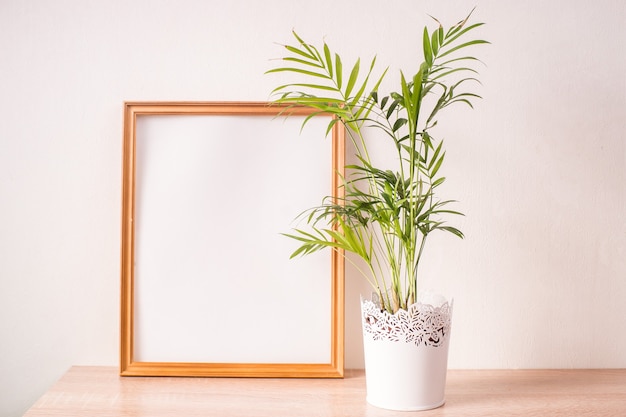 Portret broun fotolijst mockup op houten tafel. Witte muur achtergrond. Scandinavisch interieur.