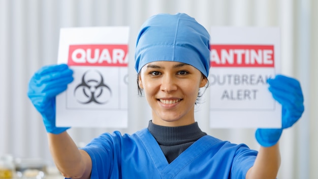 Portret close-up shot van gelukkige mooie dokter in blauw ziekenhuis uniform traan quarantaine uitbraak waarschuwing papier uit elkaar wanneer de pandemie van het coronavirus eindigt en het normale leven en het bedrijfsleven terug zijn.