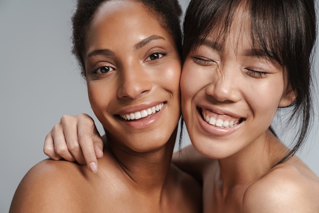 Portret close-up van twee multinationale halfnaakte vrouwen knuffelen en lachen