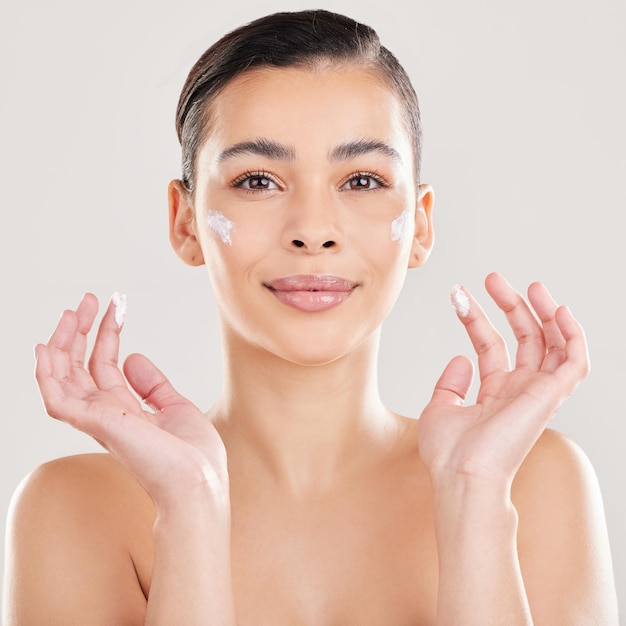Portret crème en vrouw met dermatologie glimlach en esthetiek op een witte studio achtergrond Gezicht persoon en model met lotion glans of crème met huidverzorgings moisturizer en wellness met cosmetica