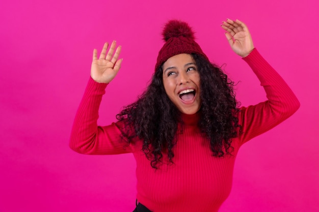 Portret curlyhaired vrouw in een wollen muts op een roze achtergrond met leuke studio opname