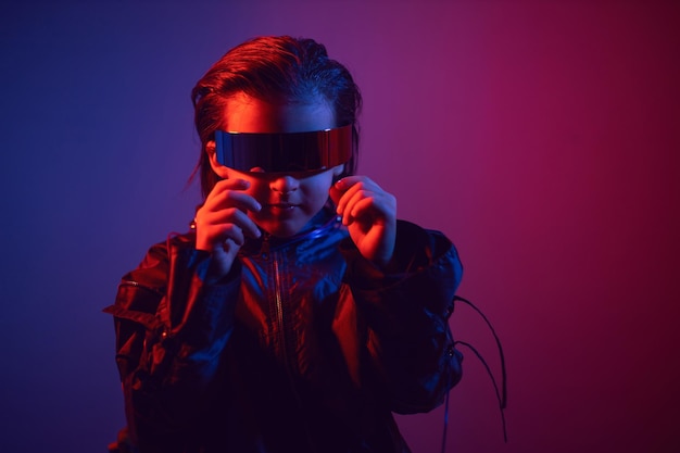 Portret cyberpunk jongenskind in vr-bril in blauwe en rode tinten met draden op een rode achtergrond