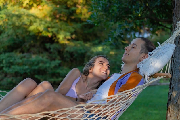 Portret dat de tienerliefde van de zomer vertegenwoordigt terwijl hij in een hangmat rust en genegenheid aan elkaar geeft in de natuur