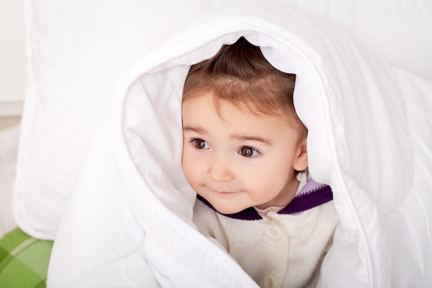 Portret dat van babymeisje in bed onder veerbed ligt