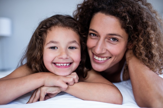 Portret dat van moeder en dochter op bed omhelst