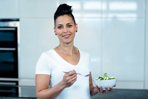 Portret dat van zwangere vrouw een kom salade en het glimlachen houdt