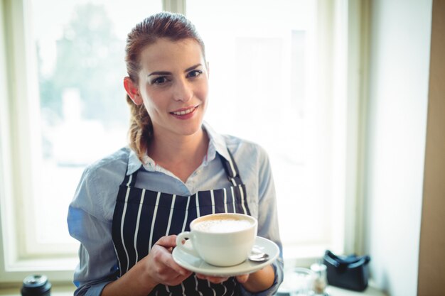 Portret die van gelukkige serveerster koffie aanbieden bij koffie