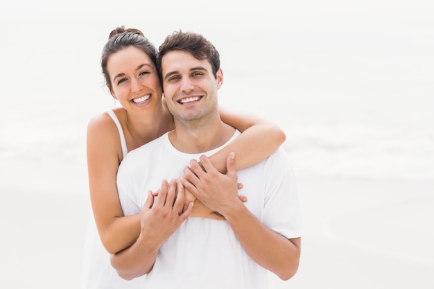 Portret die van jong paar elkaar op het strand omhelzen