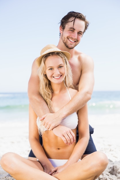 Portret die van jong paar op het strand omhelzen