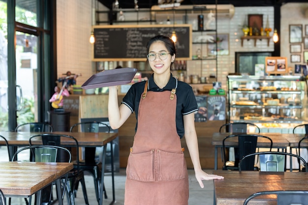 Portret die van waiteress leeg dienblad in een koffiewinkel houden.