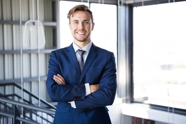 Portret die van zakenman zich met gekruiste wapens bevinden en in bureau glimlachen