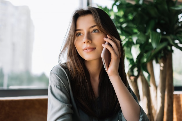 Portret die van zekere cellphone van de onderneemsterholding, in koffie zitten