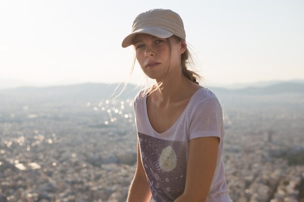 Portret dromerig en lucht aantrekkelijk meisje in een pet speels en zorgeloos met mooie glimlach op zonnige dag van de stad van Athene met Mount Lycabettus, Griekenland zoals gezien door de lucht.