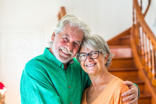 Portret en close-up van twee gelukkige senioren of volwassen en oude mensen die glimlachen en naar de camera kijken - paar gepensioneerden die thuis plezier hebben