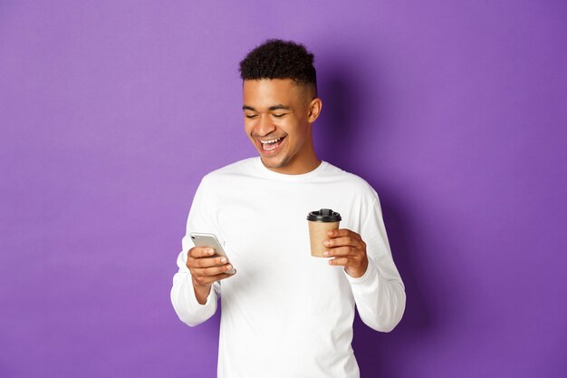 Portret expressieve jonge man met kopje koffie en mobiel