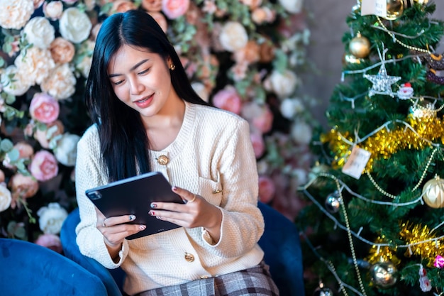 Portret freelance bedrijf mooie positieve glimlach jonge aziatische vrouw die online werkt met het gebruik van tablet thuis in de woonkamer binnenshuis of in het café Zakelijke levensstijl en rozenachtergrond