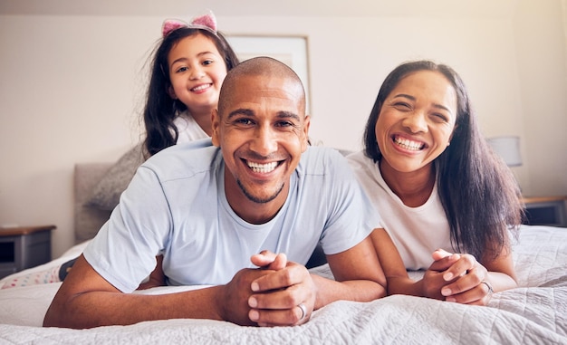 Portret gelukkig en een gezin ontspannen op een bed thuis terwijl lachen en spelen voor kwaliteit tijd Man vrouw of Spaanse ouders en kind samen in de slaapkamer voor de ochtend binden met liefde en zorg