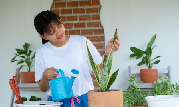 Portret gelukkig jong meisje dat groene planten thuis water geeft Aziatisch meisje