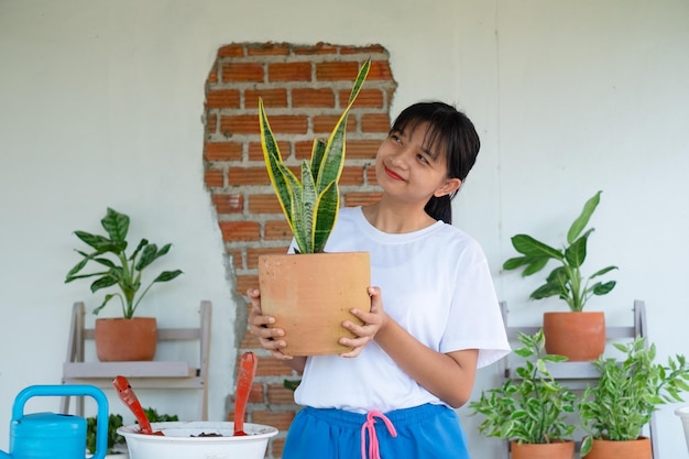 Portret gelukkig jong meisje met groene planten thuis Aziatisch meisje