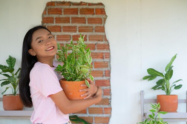 Portret gelukkig jong meisje met groene planten thuis Aziatisch meisje