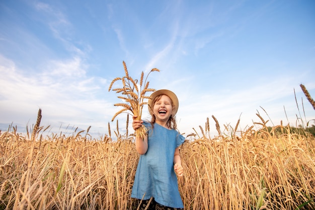 Portret gelukkig kind in een veld van tarwe trekt zijn handen naar de top