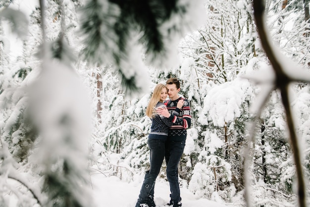 Portret gelukkig liefdevol paar buitenshuis knuffelen staande in winter forest park.