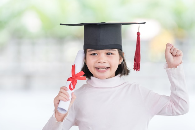 Portret gelukkige Aziatische vrouwelijke schooljongen afgestudeerd in een afstudeerpet heeft een opgerold certificaat. Afstuderen Viering Concept Stock Photo