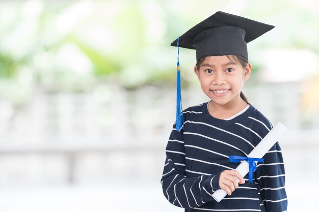 Portret gelukkige Aziatische vrouwelijke schooljongen afgestudeerd in een afstudeerpet heeft een opgerold certificaat. Afstuderen Viering Concept Stock Photo