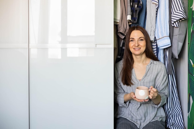 Portret gelukkige binnenlandse vrouw poseren garderobe opslag organisatie houten meubelkast ontwerp