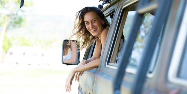 portret gelukkige blanke vrouw rijdt in een oude vintage camper op de weg. familie reis vakantie