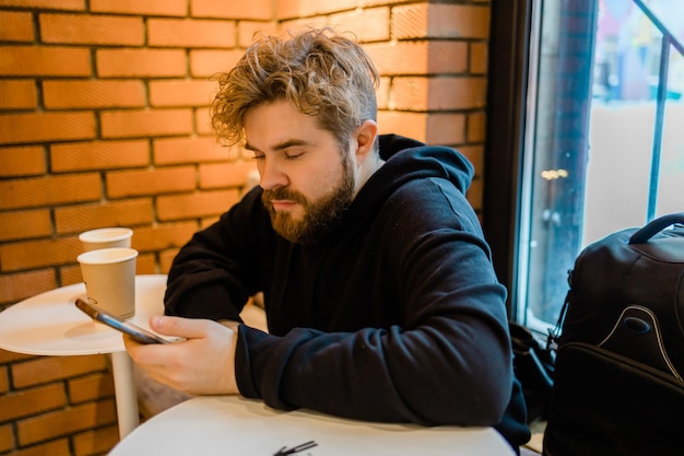 Portret gelukkige man geldtransactie maken via applicatie op mobiele telefoon met 4g internet zittend in café in straatavond serieuze millennial man die tekstbericht op smartphone leest