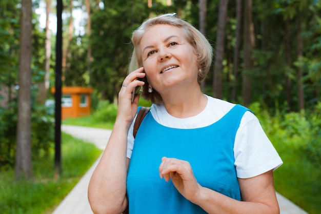 Portret gelukkige oudere vrouw lopen op park praten met communiceren praten mobiele telefoon