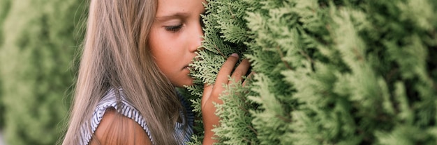 Portret gezicht van openhartig beledigd boos klein meisje van acht jaar oud met lang blond haar op de achtergrond van groene planten tijdens een zomervakantie reizen gen z geestelijke gezondheid concept banner