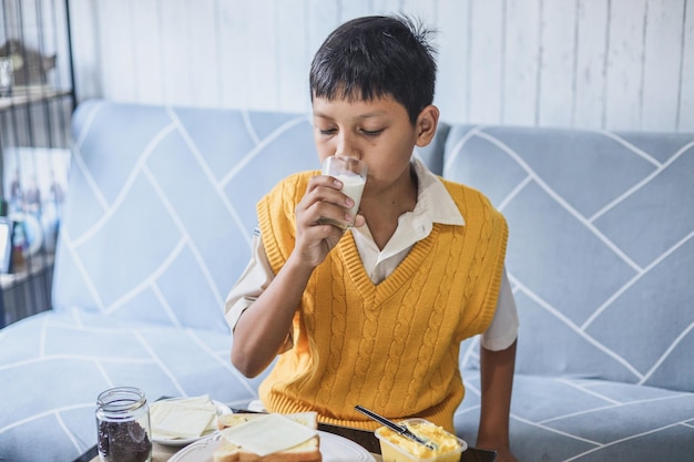 Portret gezonde schooljongen in uniform glas melk drinken voor het ontbijt voordat hij naar school gaat.