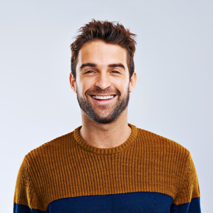 Foto portret glimlach en man met positief vertrouwen en zorgeloos tegen een grijze studio achtergrond gezicht mannelijke persoon en mens met een vrolijke houding vrijheid en model met vreugde canada en ontspan