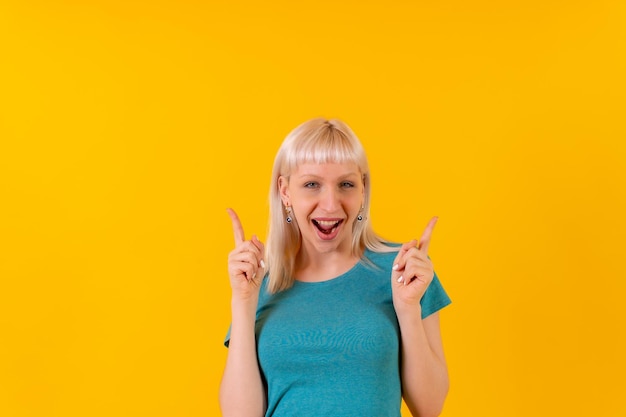 Portret glimlachend blond blank meisje in studio op gele achtergrond