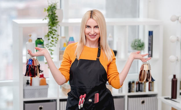 Portret of hairdresser in salon holding in her hands colorful samples for hair dyeing