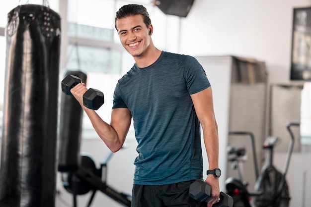 Portret halters en man in de sportschool glimlachen met koptelefoon voor het streamen van muziek tijdens het sporten Sporttraining fitness en gelukkige bodybuilder of atleet die gewichten opheft voor lichaamsbeweging, gezondheid en spieren