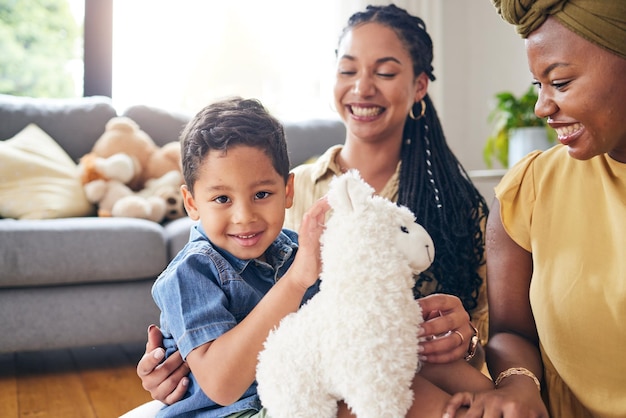 Portret homo familie en kind met een teddybeer op een thuisvloer voor ontwikkelingsplezier en glimlach Adoptie lesbische of LGBT-vrouwen of ouders en kind samen in een lounge tijdens het spelen met speelgoed