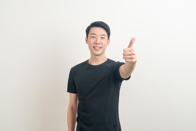 portret jonge Aziatische man duimen omhoog of ok hand teken op witte achtergrond