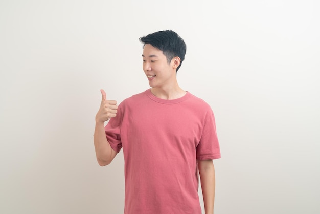 portret jonge Aziatische man duimen omhoog of ok handteken op witte achtergrond