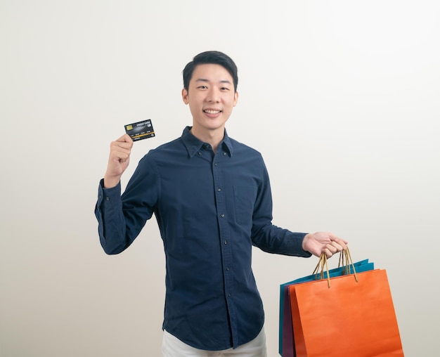 Portret jonge Aziatische man met creditcard en boodschappentas
