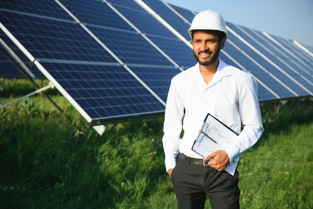 Portret jonge Indiase technicus of manager in formele kleren die staat met een zonnepaneel hernieuwbare energie man die staat met de arm gekruist kopieer ruimte