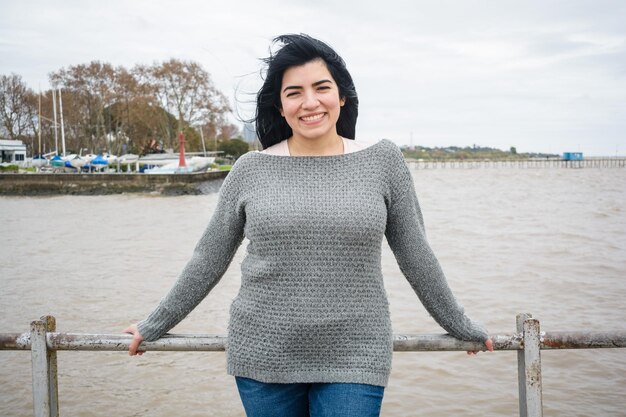 portret jonge latijns-vrouw toeristische glimlachend staande op de pier over de rivier