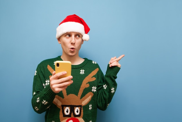 Portret jonge man met kerstmuts met telefoon