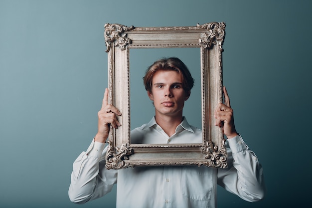 Portret jonge man permanent met afbeeldingsframe in studio.