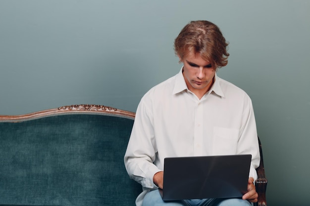 Portret jonge man zit met laptop in studio