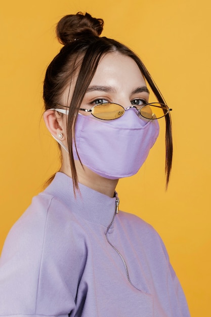 Portret jonge vrouw die zonnebril en masker draagt