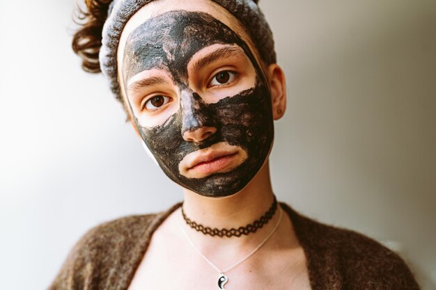 Portret jonge vrouw met klei gezichtsmasker op gezicht