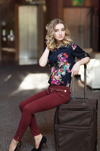 Portret jonge vrouw zittend op koffers in de terminal of het treinstation, De vrouw ontmoette op een reis.